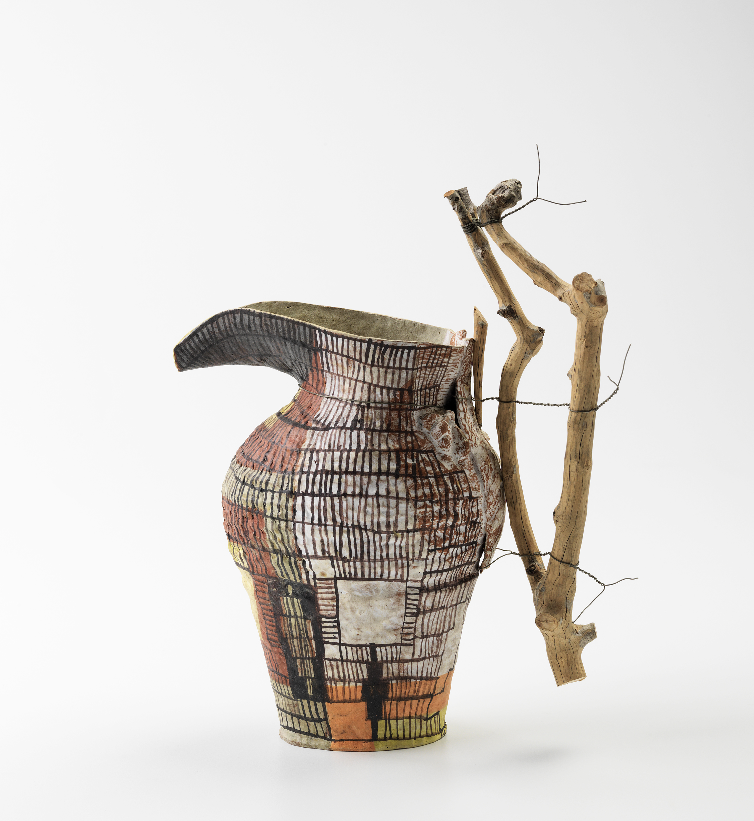 Terracotta jug with an extended lip and large sandalwood handle tied to the body of the jug with wire. The body of the vessel has painted grid-like patterns.