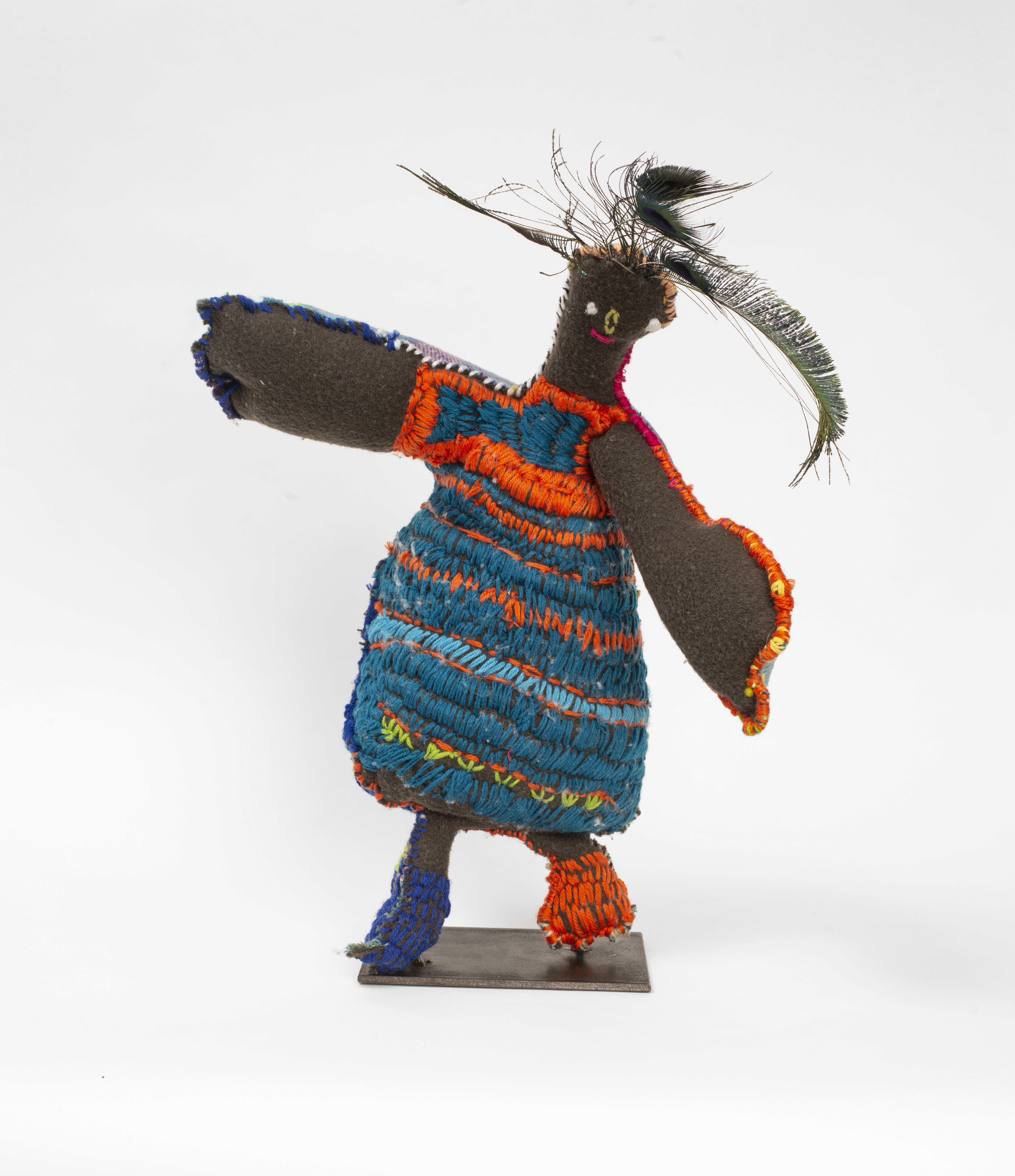 Sewn textile sculpture of a woman wearing a brightly coloured dress and feathers in her hair